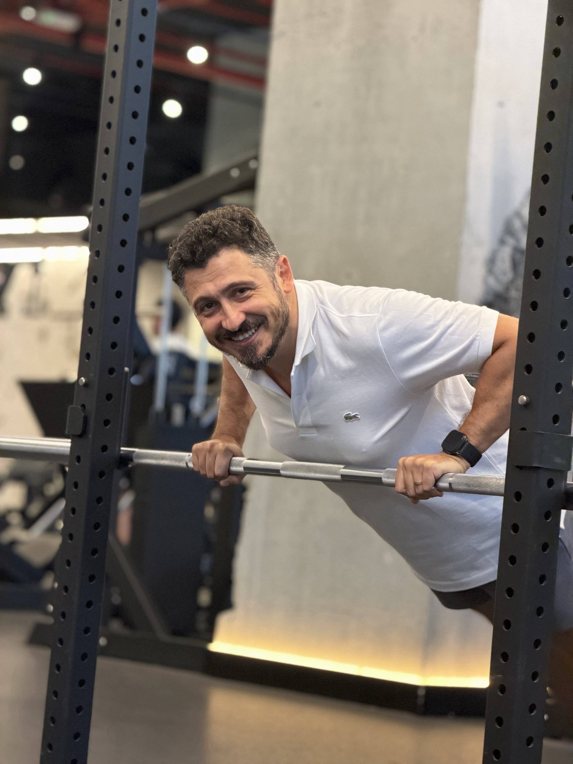 Client smiling at the squat rack during a strength session