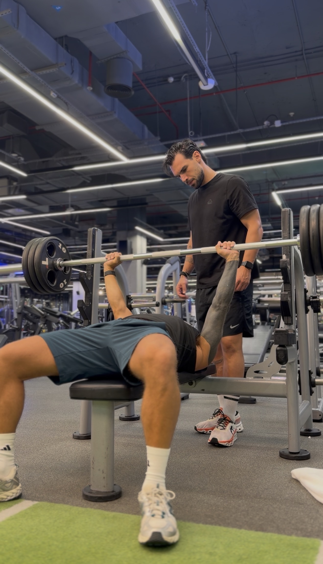 Coach spotting a client during a barbell bench press