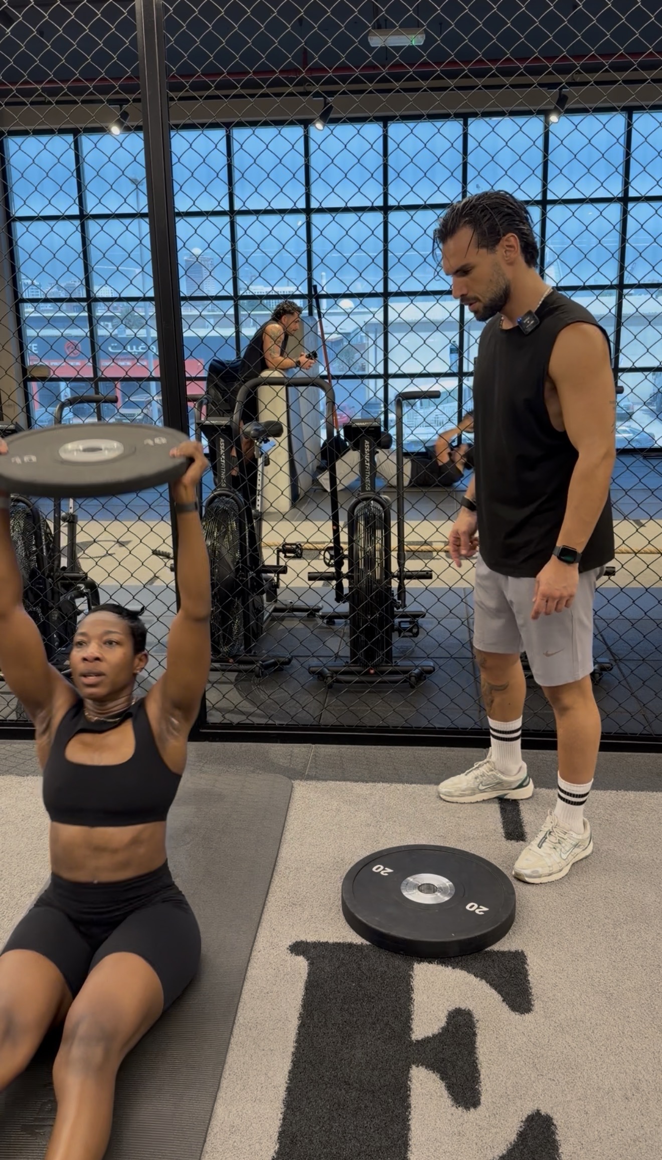 NOVABODY coach guiding a client through a seated overhead plate press